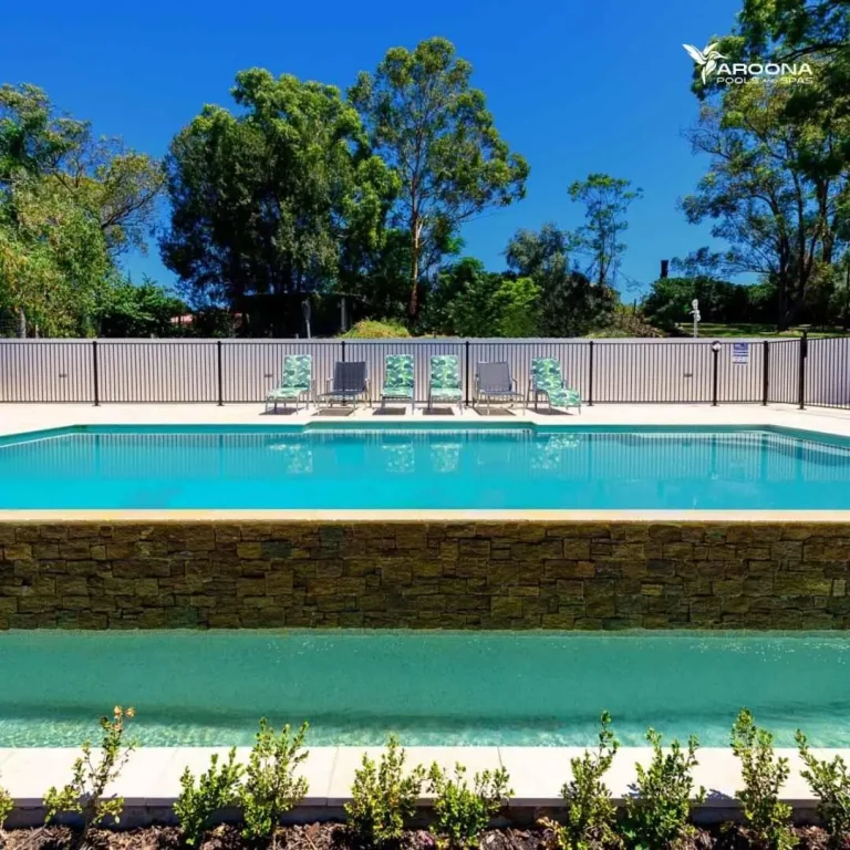 Infinity edge swimming pool with stone retaining wall and elevated backyard design in Castle Cove NSW