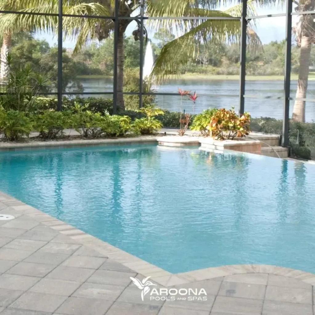 Screened backyard swimming pool with lake view and tropical landscaping