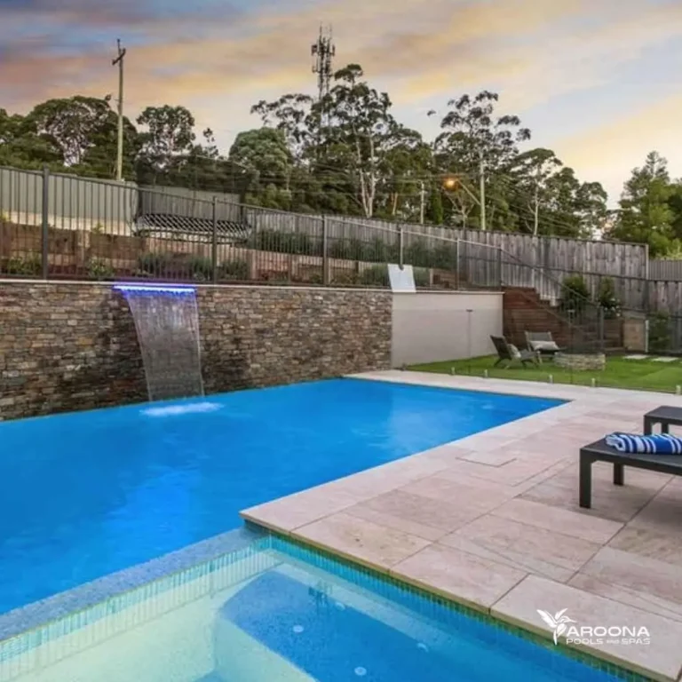 Large concrete luxury swimming pool with stone wall waterfall feature and spacious patio area in Castle Hill NSW