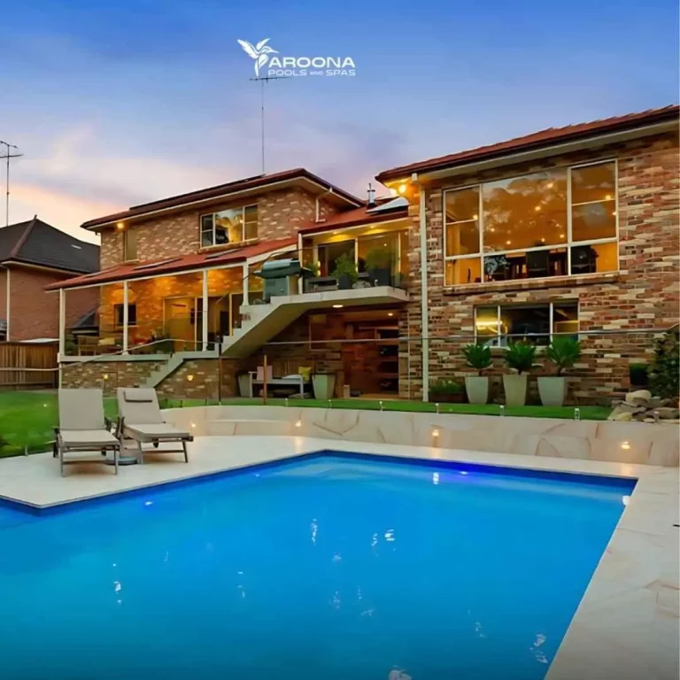 Luxury backyard swimming pool at dusk with modern double-storey home and outdoor lighting