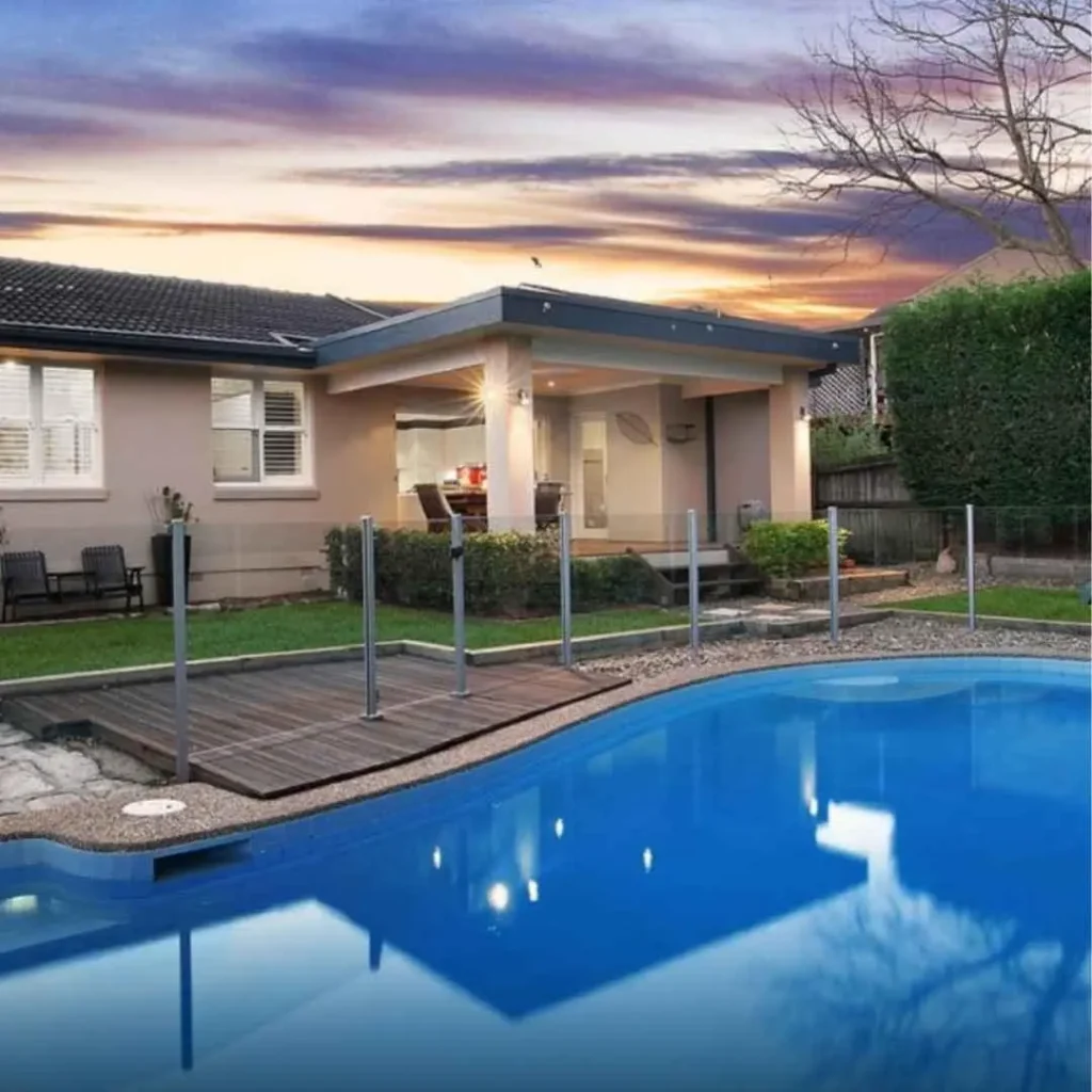Family-friendly backyard concrete swimming pool with timber deck and glass fencing in Seaforth NSW