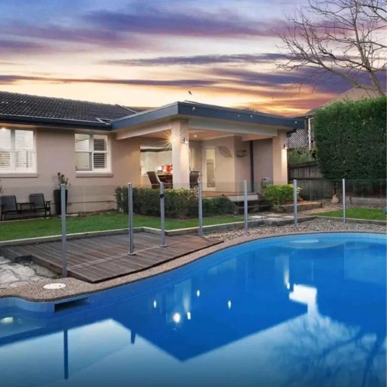 Family-friendly backyard concrete swimming pool with timber deck and glass fencing in Seaforth NSW